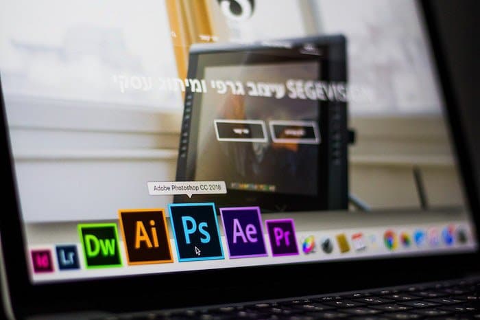 un primer plano de una persona que elige el ícono de Photoshop en una computadora portátil para editar fotografías de comercio electrónico