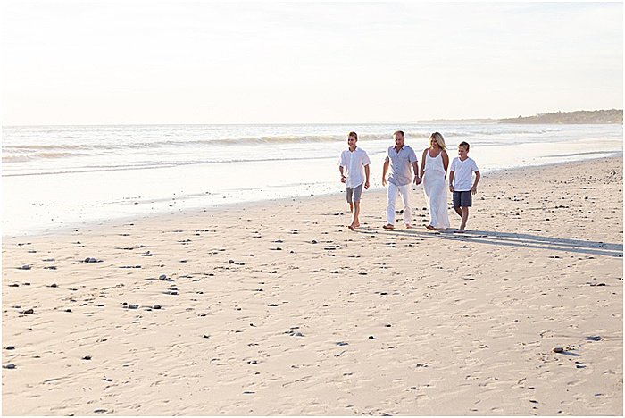 Un retrato divertido e informal de una familia de cuatro personas posando en la playa - fotografía emocional