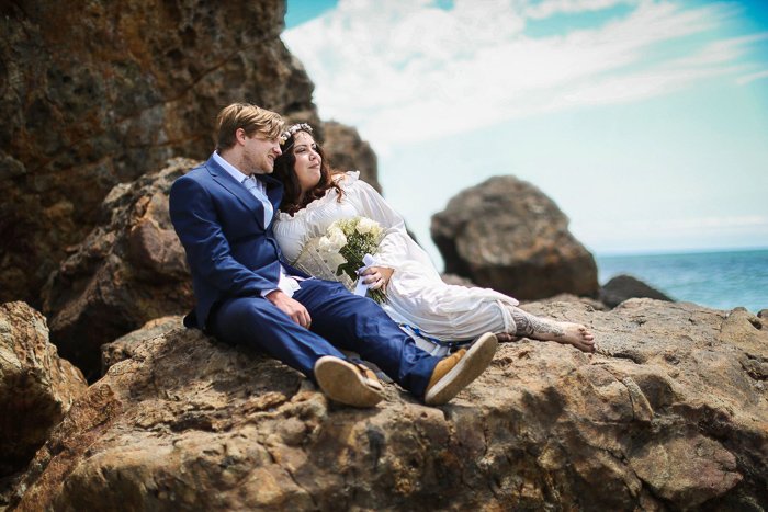 Una pareja de recién casados ​​recostados sobre las rocas en la playa: consejos para la fotografía de eventos