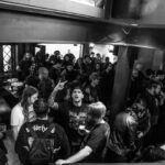 Fotografía de un evento en blanco y negro de una multitud en el interior de un bar o sala de conciertos