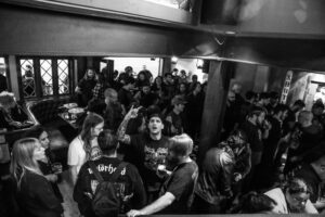 Fotografía de un evento en blanco y negro de una multitud en el interior de un bar o sala de conciertos
