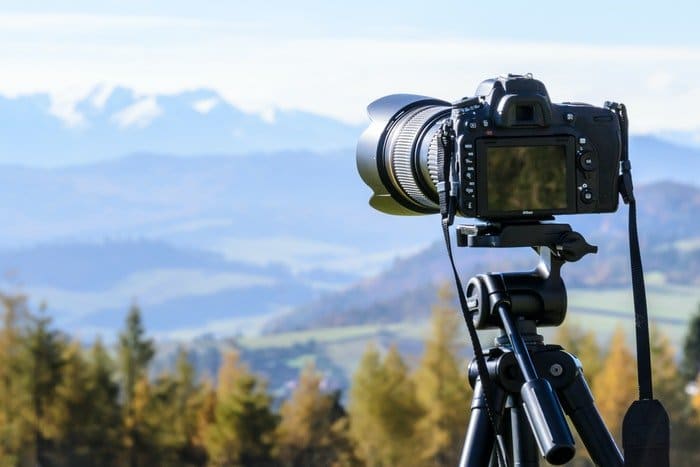 Una cámara en un trípode con un paisaje de montaña.