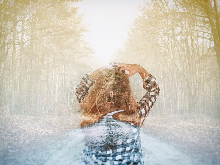 Una imagen de doble exposición de una niña caminando por un bosque