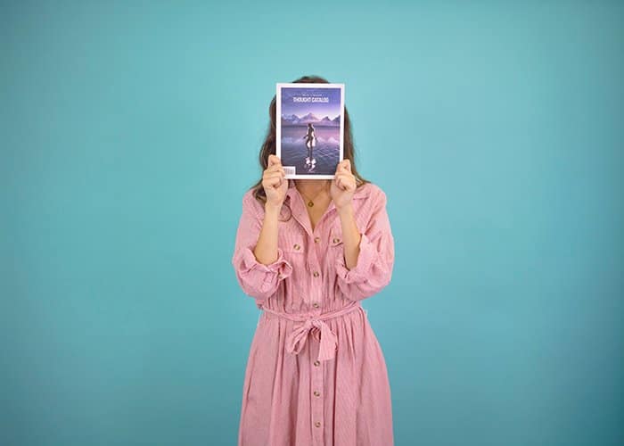 Una mujer vestida de rosa usa una revista para crear un retrato sin rostro para anunciar su negocio