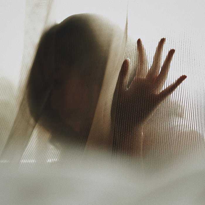Retrato sin rostro etéreo de una mujer detrás de una cortina semi transparente