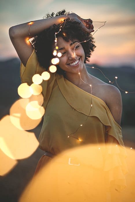 Un creativo retrato al aire libre de una modelo femenina sosteniendo una cadena de luces - fotografía de luces de hadas