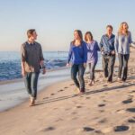 Una linda sesión de fotos familiares en la playa con la familia caminando cerca de la orilla con atuendos coordinados