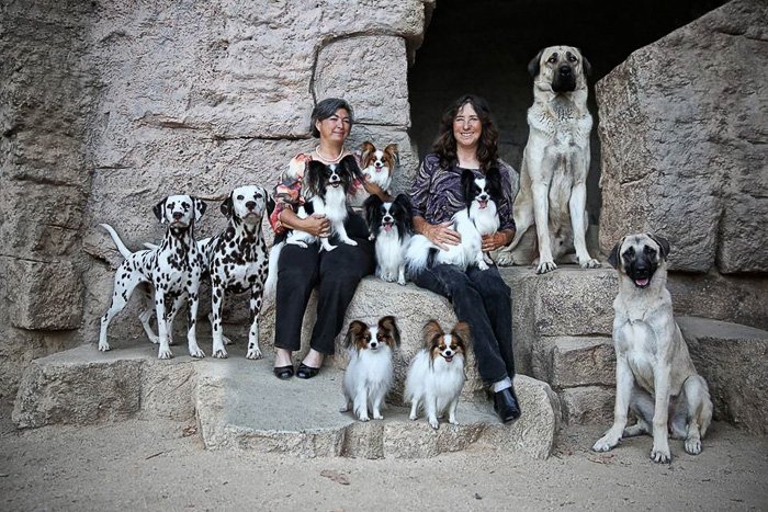 dos mujeres con muchos perros posando para un retrato familiar