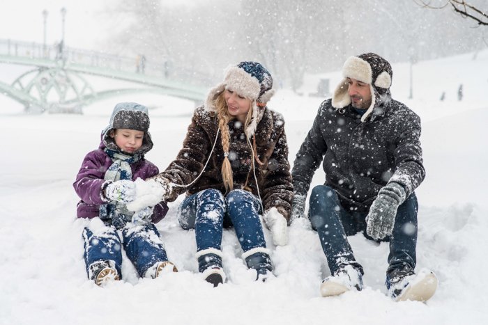 familia de tres sentados en la nieve