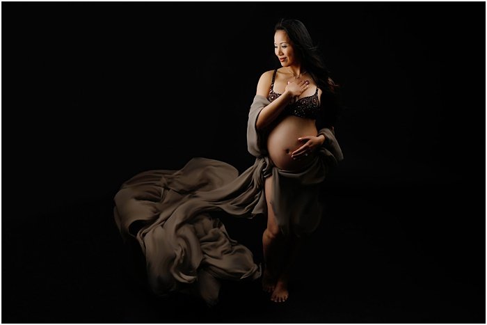 Foto de una mujer embarazada frente a un fondo negro