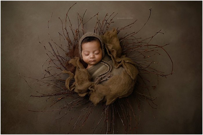 Foto artística de un bebé frente a un fondo marrón.