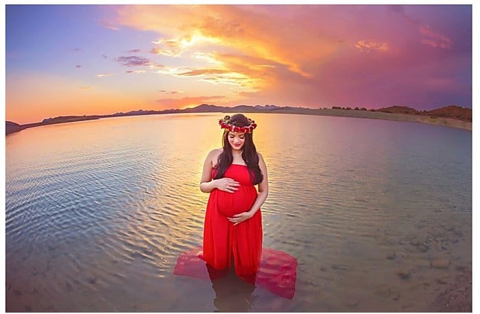 Foto de una mujer embarazada de pie en el agua al atardecer