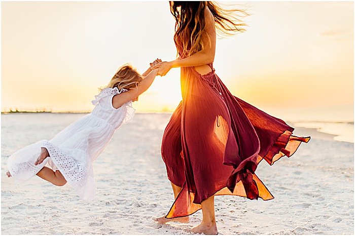 Foto de una mujer jugando con una niña en la playa.