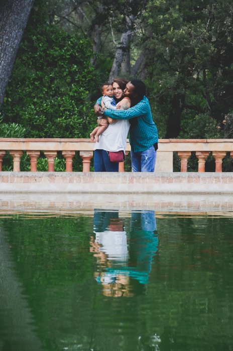 Una pareja con un bebé pequeño posando frente a un estanque: composición para ideas de fotos familiares