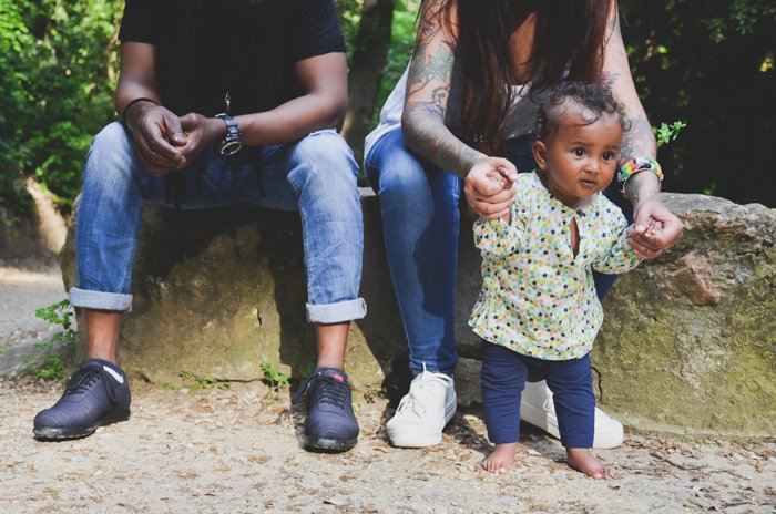 Cierra la foto familiar de una mujer sosteniendo las manos de un bebé pequeño con un hombre a su lado