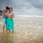 Una pareja con un bebé pequeño posando en la playa: consejos de composición para la fotografía familiar.