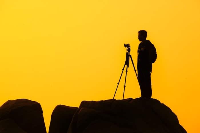Un fotógrafo de vida salvaje recortado contra la puesta de sol