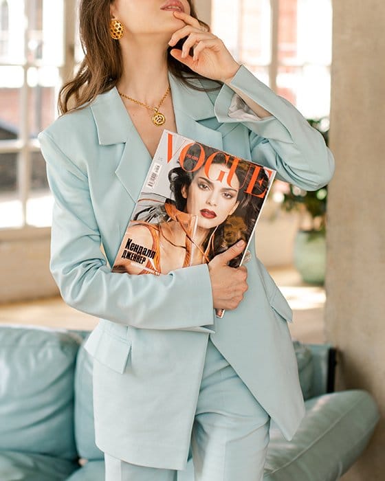 Foto de una mujer con traje azul sosteniendo una revista Vogue