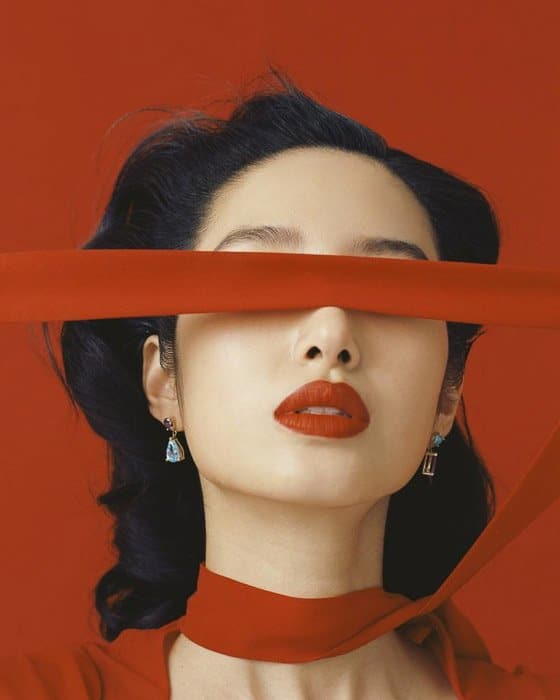 Un modelo de moda con bufanda roja sobre fondo rojo de Leslie Zhang, por ejemplo