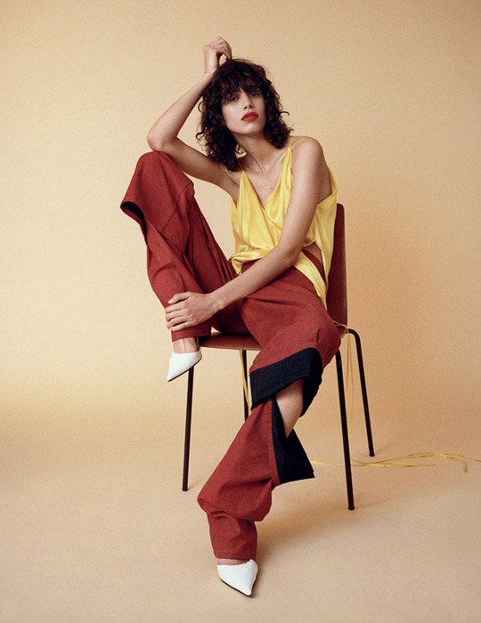 Una modelo femenina posando en una silla con un fondo amarillo pálido - inspiración fotográfica de moda