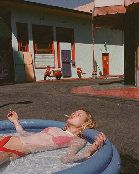 Una modelo rubia en una piscina de plástico fumando un cigarrillo por v - inspiración de fotografía de moda