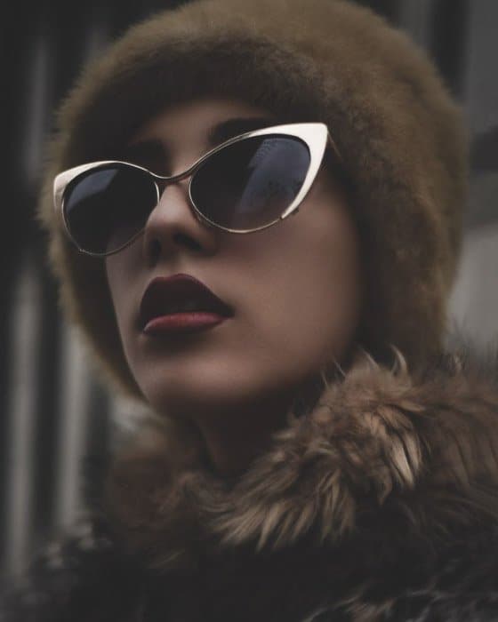 Una foto de moda editorial de belleza de una modelo femenina posando con gafas de sol y pieles - tipos de fotografía de moda