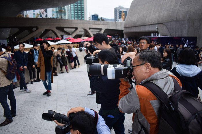 Un grupo de fotógrafos disparando un retrato de moda de una modelo femenina al aire libre