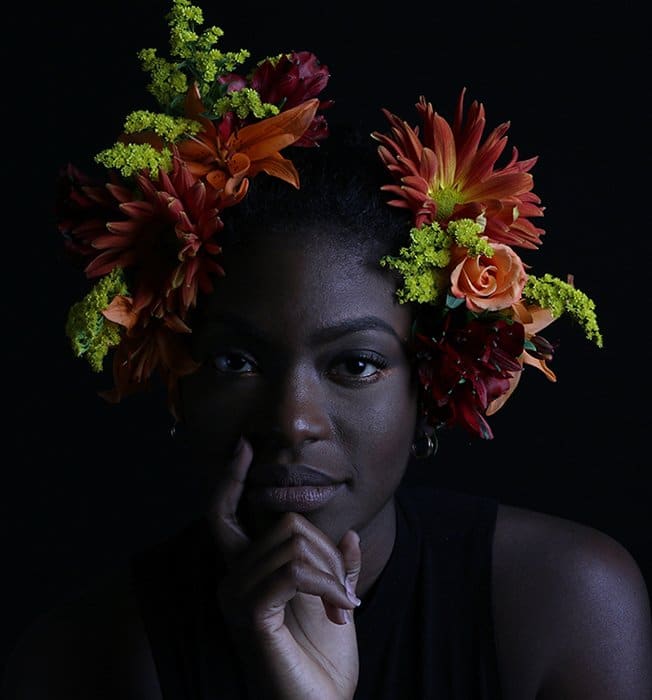 Retrato atmosférico de una modelo femenina posando en el interior con flores en el pelo: cómo fotografiar el rostro femenino