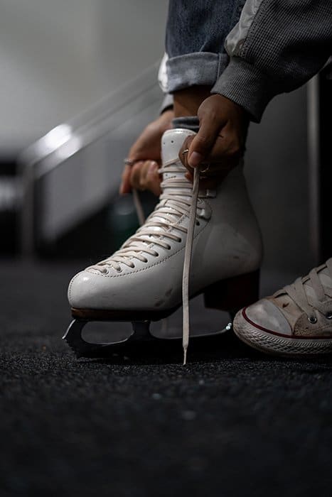 Perder a un patinador atando los cordones de sus patines de hielo