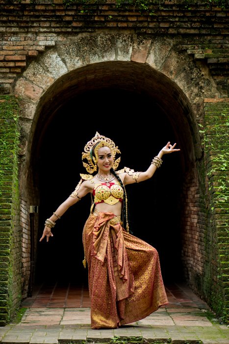 Una bailarina tailandesa sonriente bellamente disfrazada posa frente a un túnel: consejos de composición fotográfica