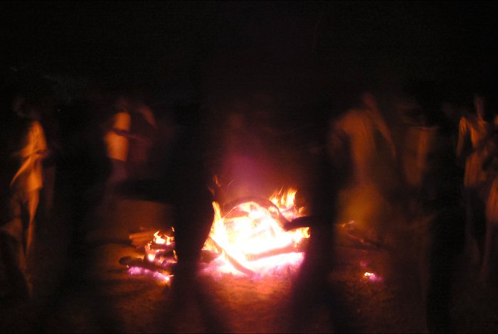 Toma de fotografía de viajes atmosféricos de personas bailando alrededor de un fuego