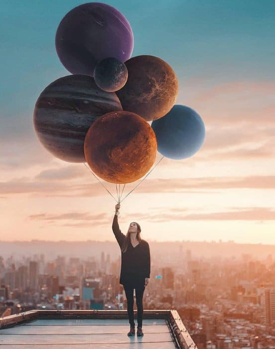 Fotografía artística de una niña sosteniendo planetas como globos