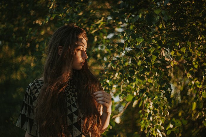 Autorretrato atmosférico de una modelo femenina posando al aire libre rodeada de árboles: errores de fotografía artística