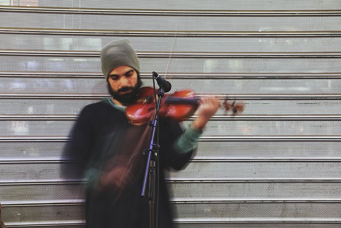 Retrato borroso de un artista callejero tocando el violín: errores de fotografía artística