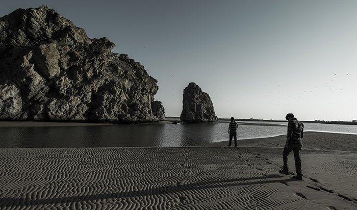 Una fotografía de bellas artes en blanco y negro de una playa rocosa, con un suave efecto brumoso del agua alrededor de las rocas y los acantilados