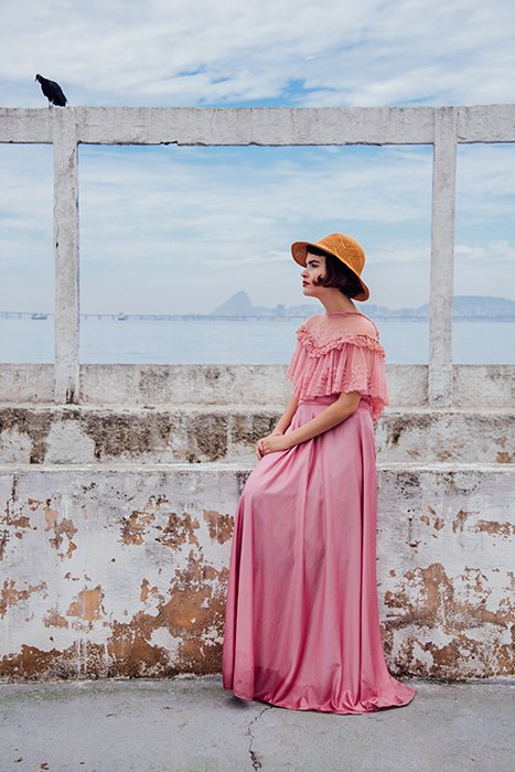 Una modelo de moda femenina posando al aire libre con un vestido rosa vintage