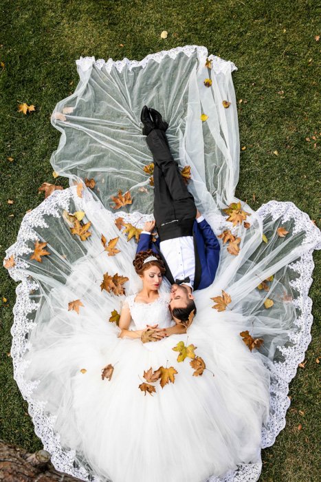 Fotografía cenital artística de una pareja de recién casados ​​tendida en el césped - fotografía de bodas de bellas artes