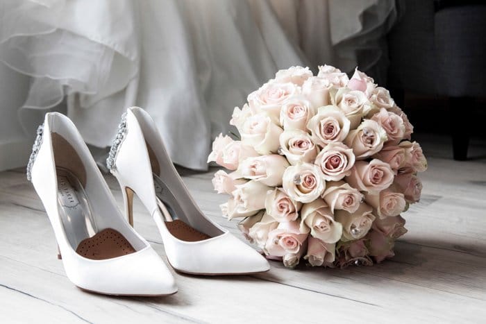 Bodegón artístico de un ramo de novia y zapatos sobre tablas de madera - fotografía de boda de bellas artes