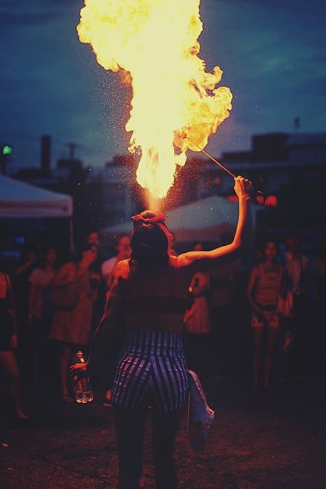 Un bailarín de fuego respirando llamas durante un festival por la noche