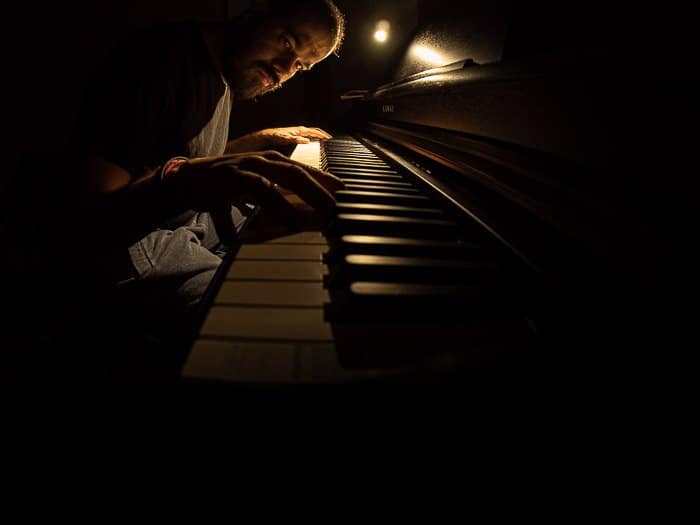 Foto de ojo de pez atmosférico de un hombre tocando el piano con poca luz