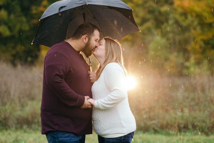 Retrato al aire libre de una pareja besándose bajo un paraguas
