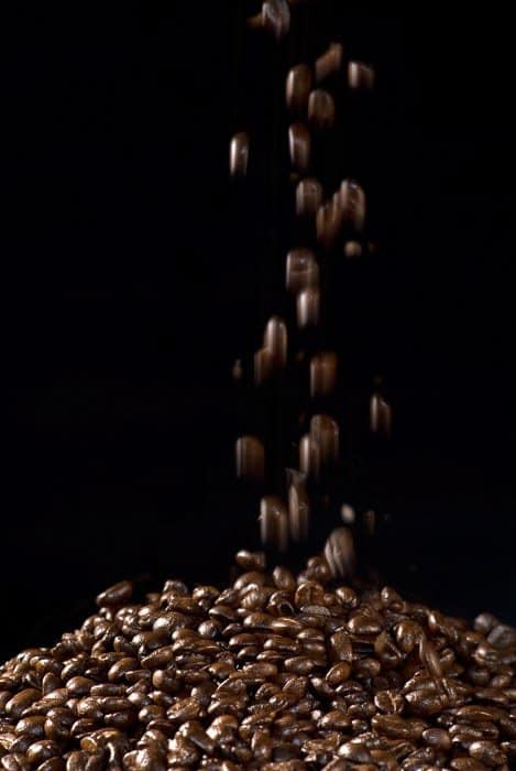 Fotografía con flash de la caída de granos de café contra un fondo negro