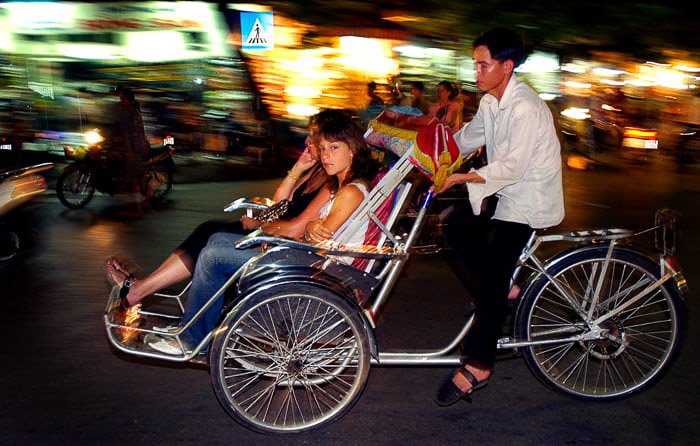Fotografía con flash de turistas en ciclo taxi, Hanoi, Vietnam