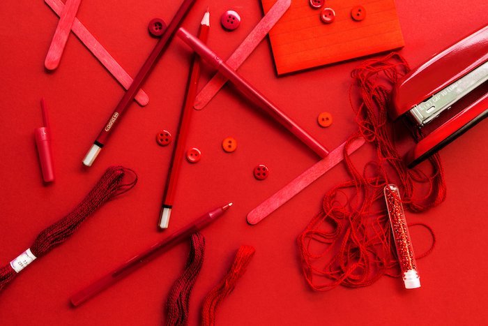 fotografía plana: lápices esparcidos sobre una superficie roja