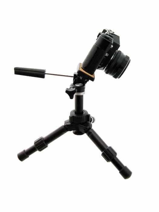 Una cámara DSLR inclinada hacia adelante sobre un trípode para fotografía de productos planos