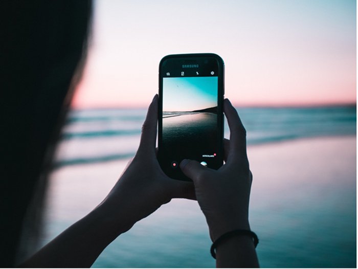 persona tomando fotos de teléfonos inteligentes en la playa