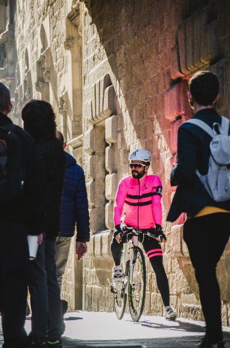Vista de la calle de personas con enfoque en un ciclista con una chaqueta rosa