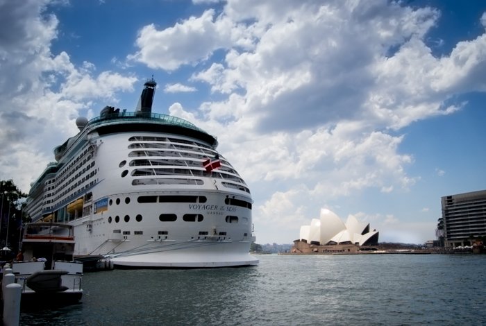 Un gran transbordador atracado en un puerto con la Ópera de Sydney detrás