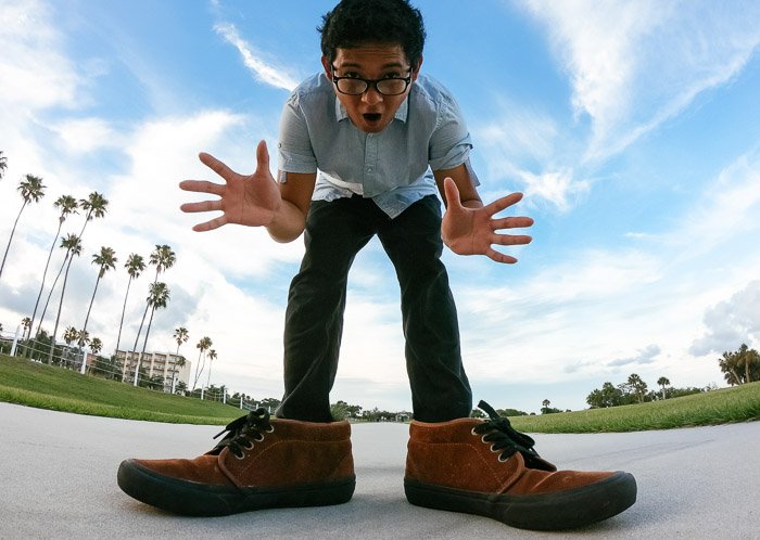 Graciosa foto de un hombre tomada en ángulo que lo hace parecer un gigante con enormes zapatos y manos