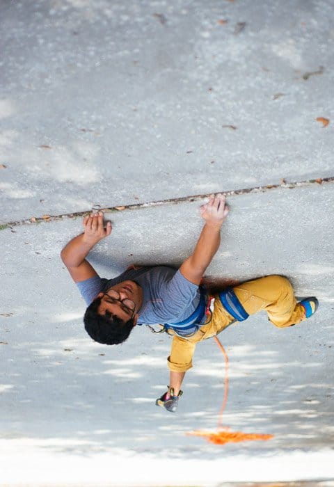 Una foto divertida de un hombre con equipo de escalada en un sendero que da la ilusión de que está escalando rocas